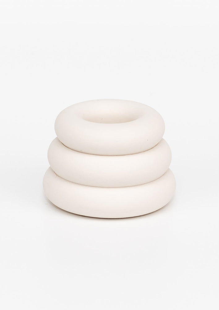 A taper candle holder with 3-layer stacked donut shape in white.