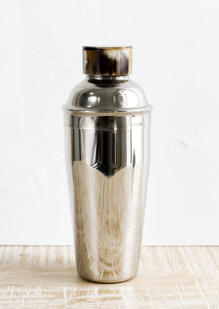 A stainless steel cocktail shaker with horn cap.