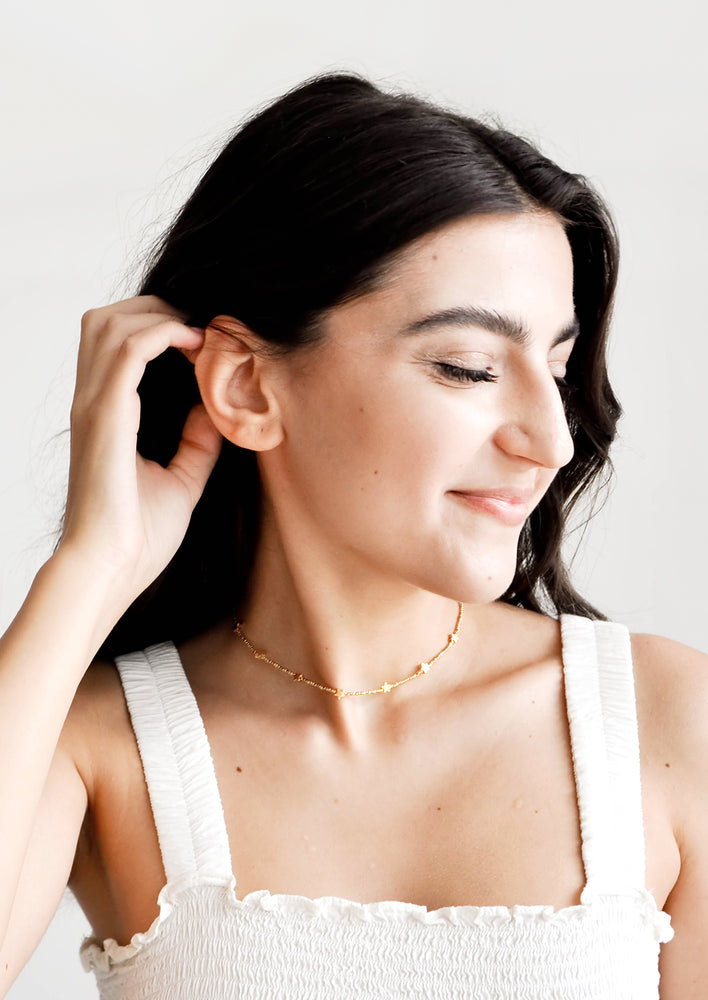Model shot of woman wearing necklace and white top.