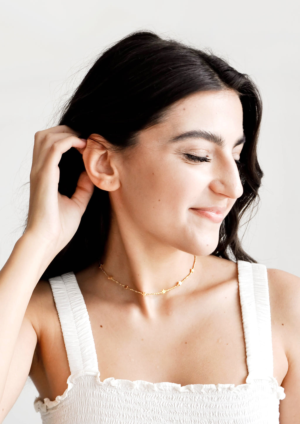 3: Model shot of woman wearing necklace and white top.