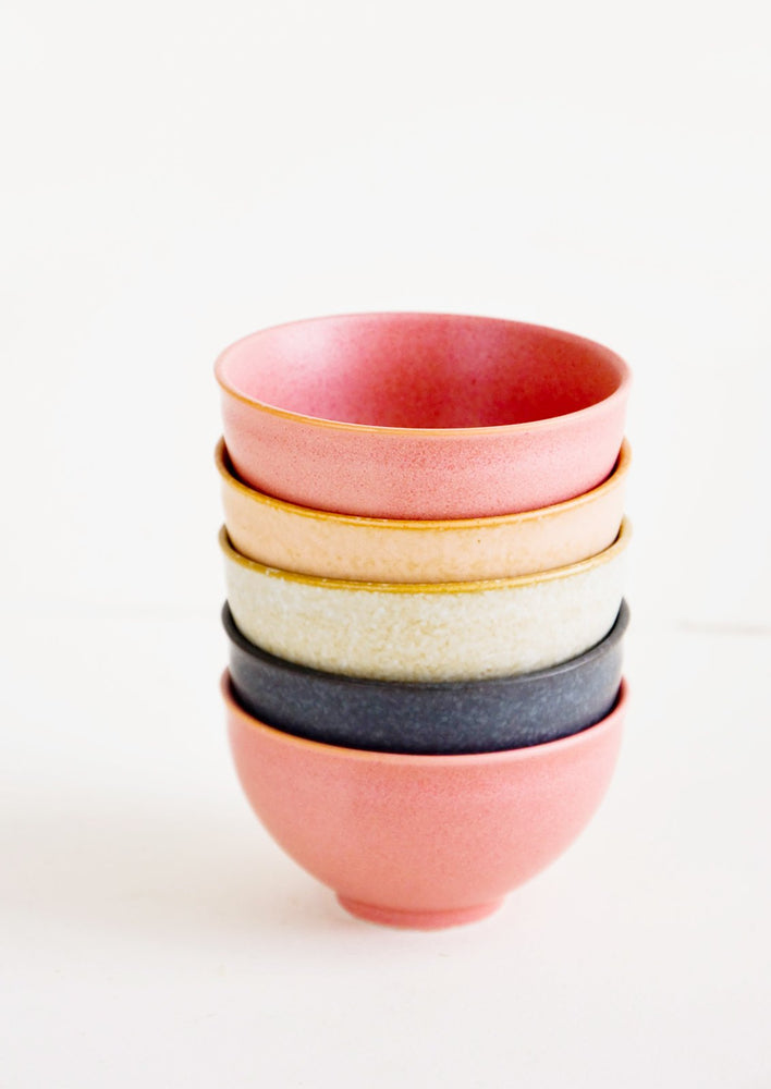 Stacked tower of small ceramic bowls in pink, peach, grey and black colors