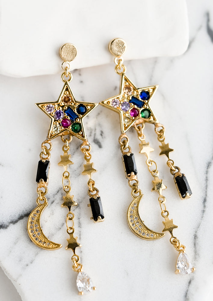 A pair of earrings with colored crystal star and strands of stars and moons.