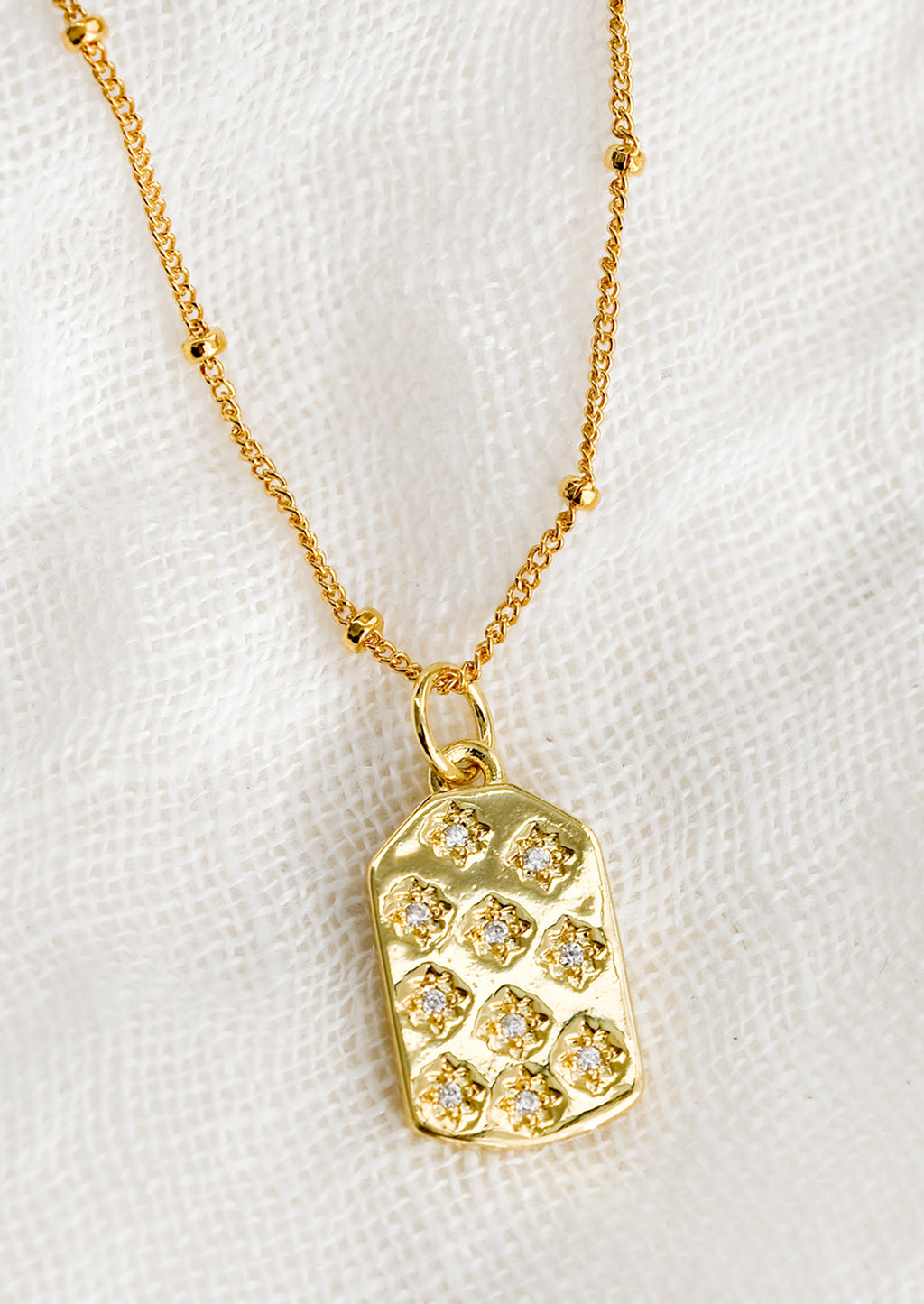 1: A gold tag charm necklace with crystal pave star detailing.