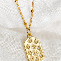 2: A gold tag charm necklace with crystal pave star detailing.