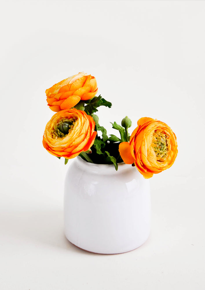 Round, white, rustic ceramic vase in glossy finish, pictured with orange flowers