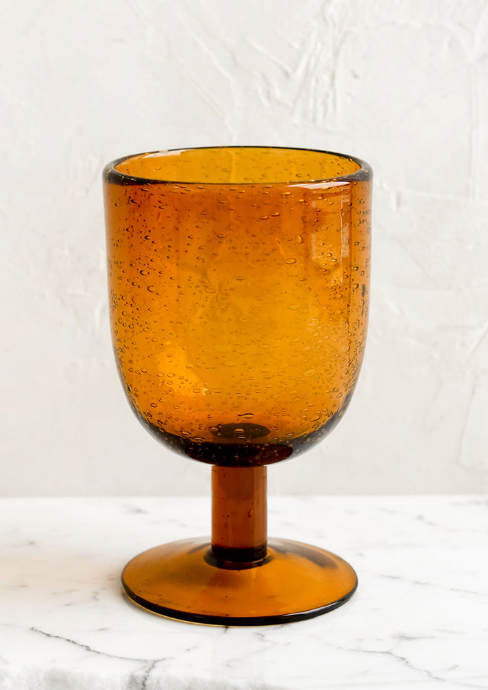 A short stemware glass in amber color.