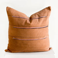 2: Throw pillow in reddish brown fabric with thin black stripes and sewn-on pink and black stripes