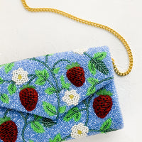 2: A blue beaded clutch with red strawberry pattern and gold chain strap.