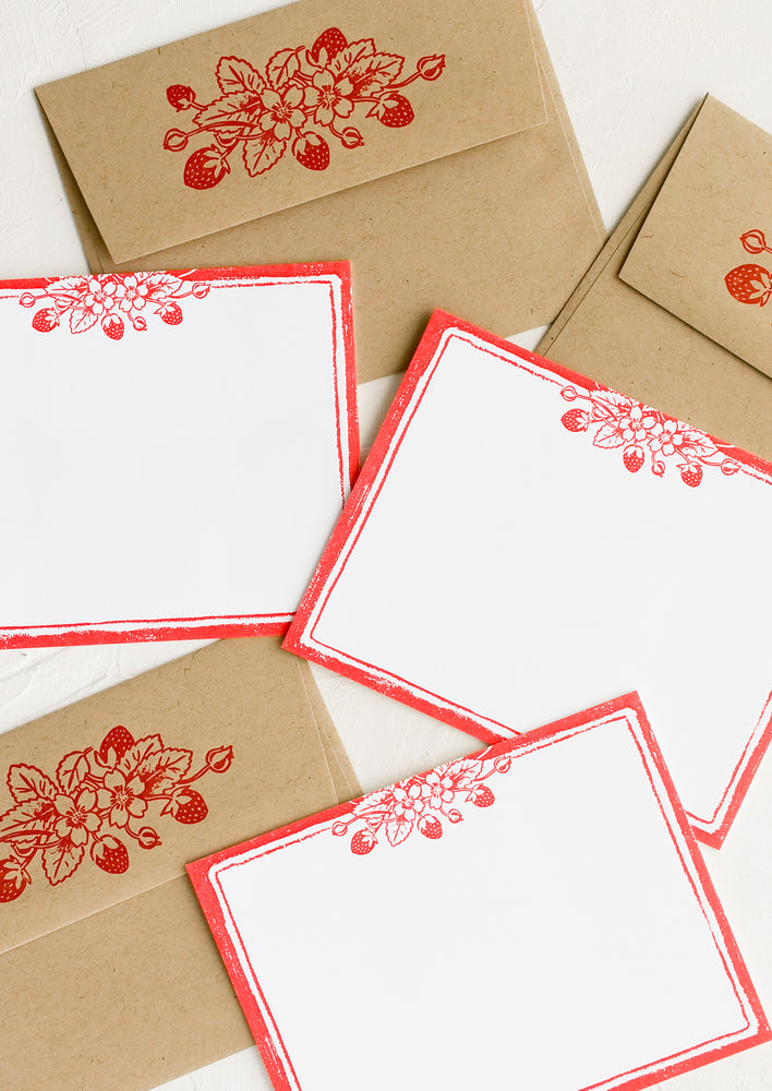 A  set of white flat notecards with strawberry print border.