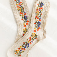 1: A pair of oatmeal colored socks with primary color strawberry print.