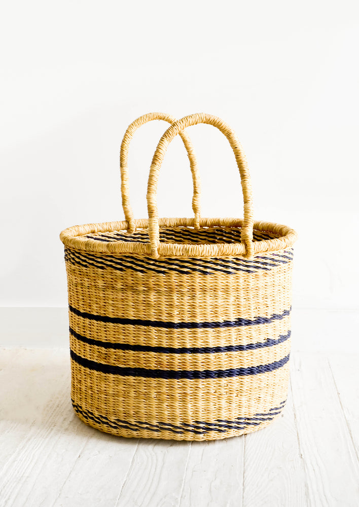 Small: Round straw storage basket with handles at top and navy blue stripes throughout