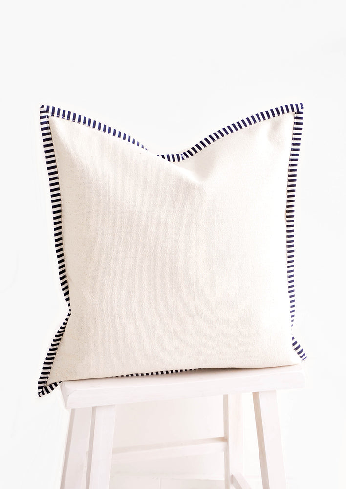 Square throw pillow in natural cotton canvas with striped navy & white trim around edges