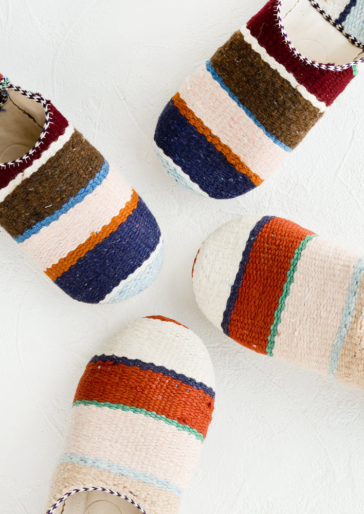 Small / Stripe: An assortment of house slippers made from wooly multicolor striped fabric.