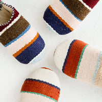 Small / Stripe: An assortment of house slippers made from wooly multicolor striped fabric.