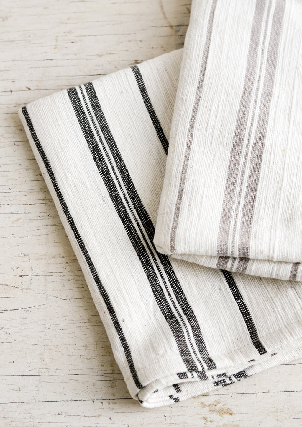 1: Two striped cotton hand towels in black and taupe colorways.