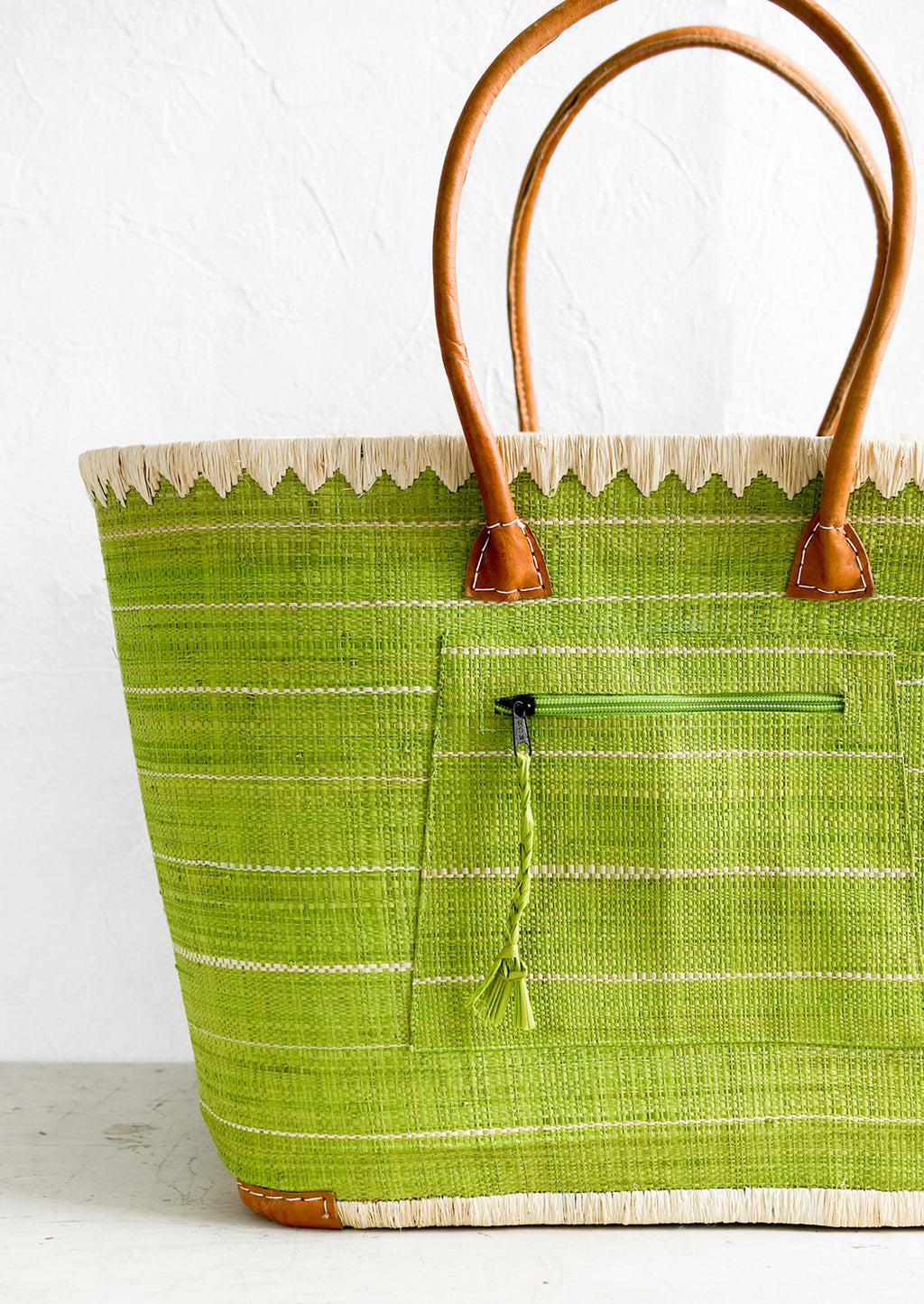 2: A raffia tote bag in green stripes with leather handles.