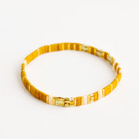 Mustard / Shell Multi: Bracelet featuring flat mustard beads interspersed with flat gold bead on an elastic cord.