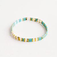 Turquoise / White Multi: Bracelet featuring flat turquoise beads interspersed with flat gold bead on an elastic cord.