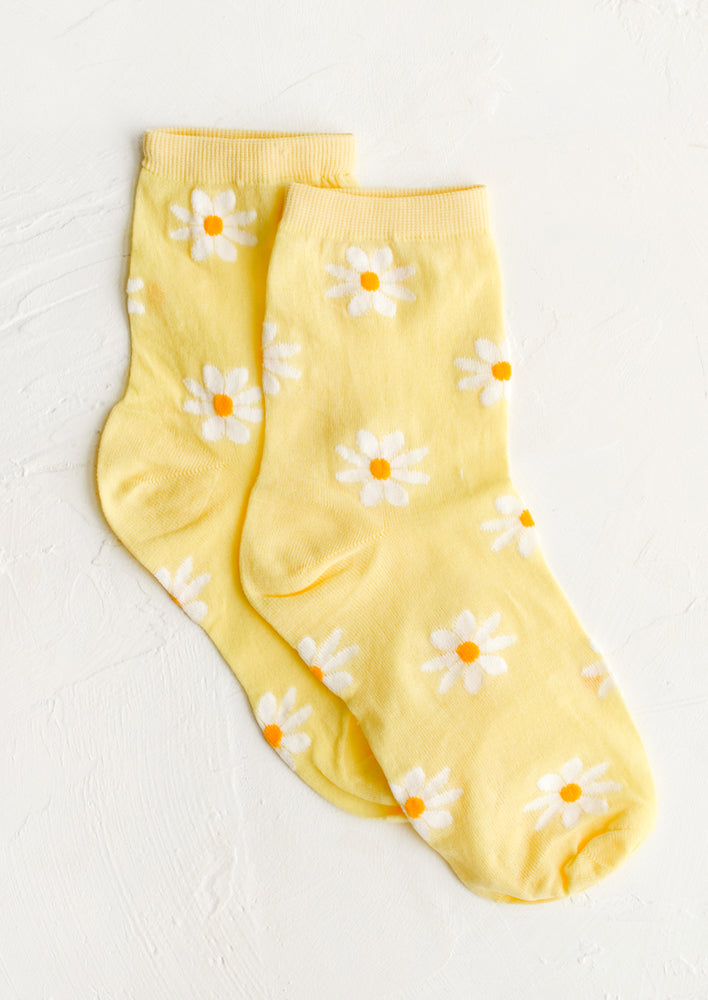 A pair of yellow socks with white daisy pattern.