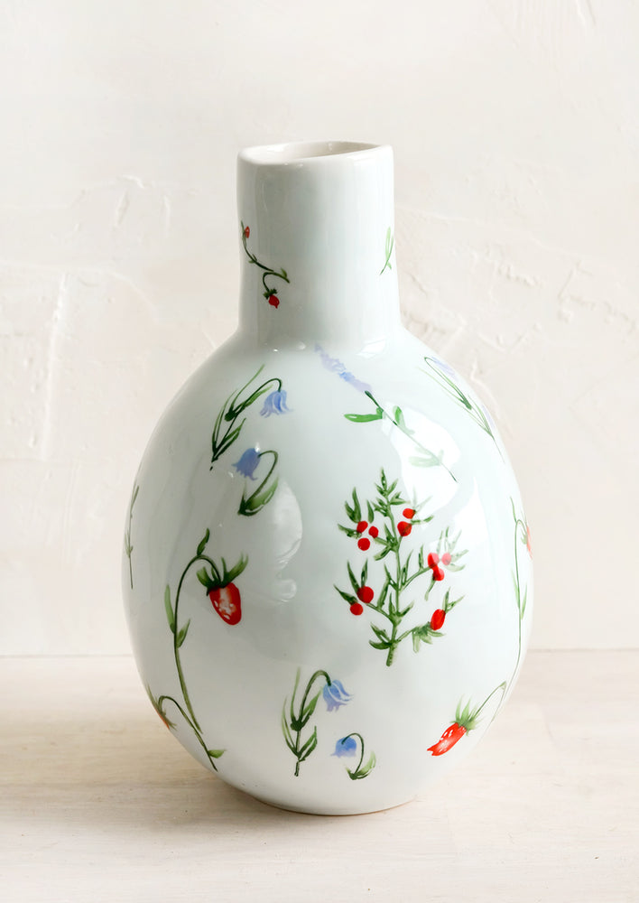 A ceramic vase with bulbous base and narrow top with painted floral print.