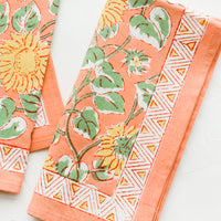 3: Pair of peach cotton napkins with yellow and green sunflower print.