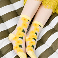 3: A woman's ankles on a hammock wearing sheer sunflower socks with yellow lace skirt.