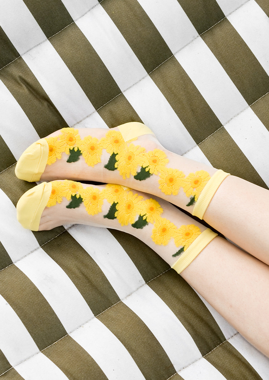 1: A woman's ankles on a hammock wearing sheer sunflower socks.