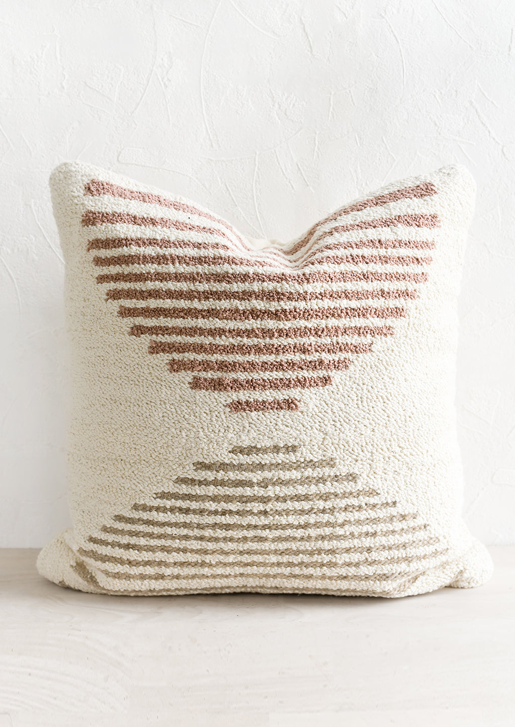 1: A tufted pillow in ivory with mauve and taupe geometric "horizon" design.