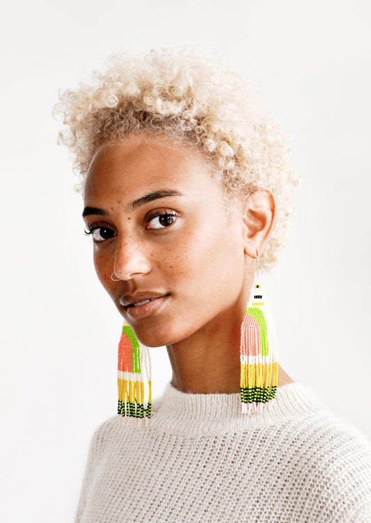 Model wears multicolored fringe beaded earrings and a sweater.