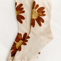 Cream: A pair of cream colored socks with fuzz textured, rust-colored flowers.