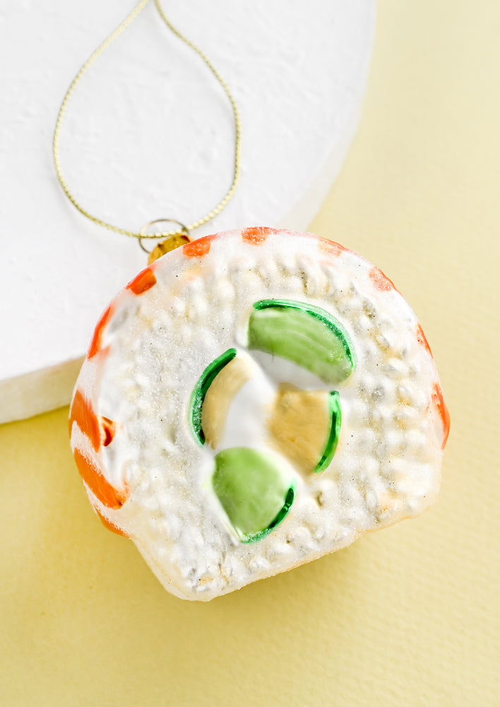 1: A decorative glass ornament in the shape of salmon avocado sushi roll.