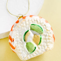 1: A decorative glass ornament in the shape of salmon avocado sushi roll.