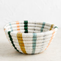 Pastel Stripes: A small woven catchall bowl made from sweetgrass in white with vertical pastel lines.