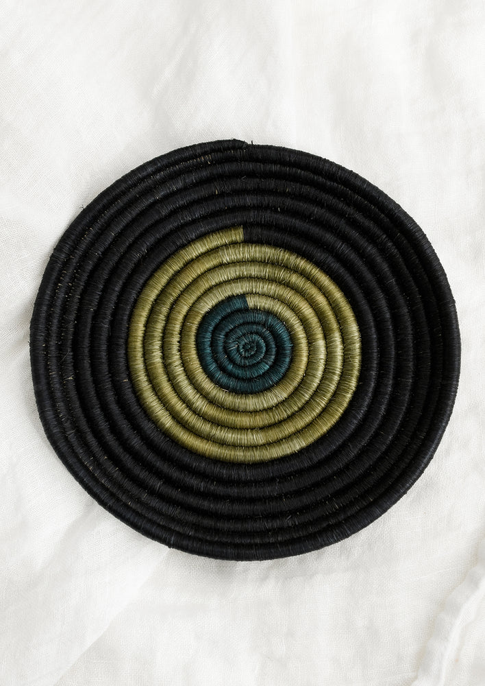 A round, shallow sweetgrass tray in black, olive green and teal.