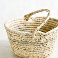 1: An oval shaped basket made from natural straw with a mobile top carrying handle.