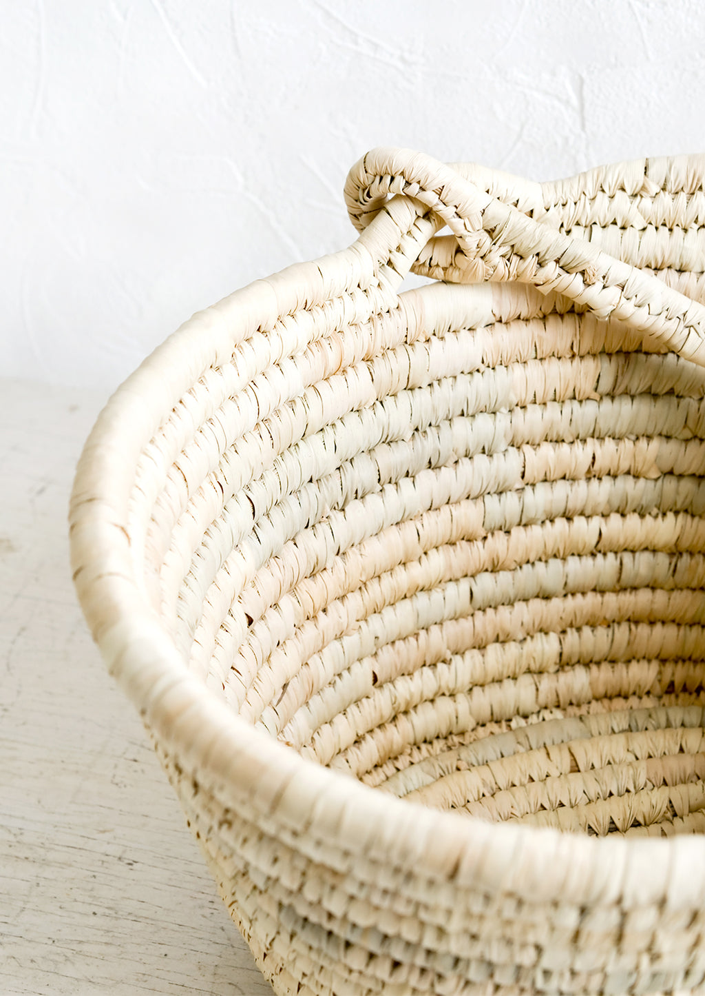 2: A swing-attached carrying handle on a natural straw basket.