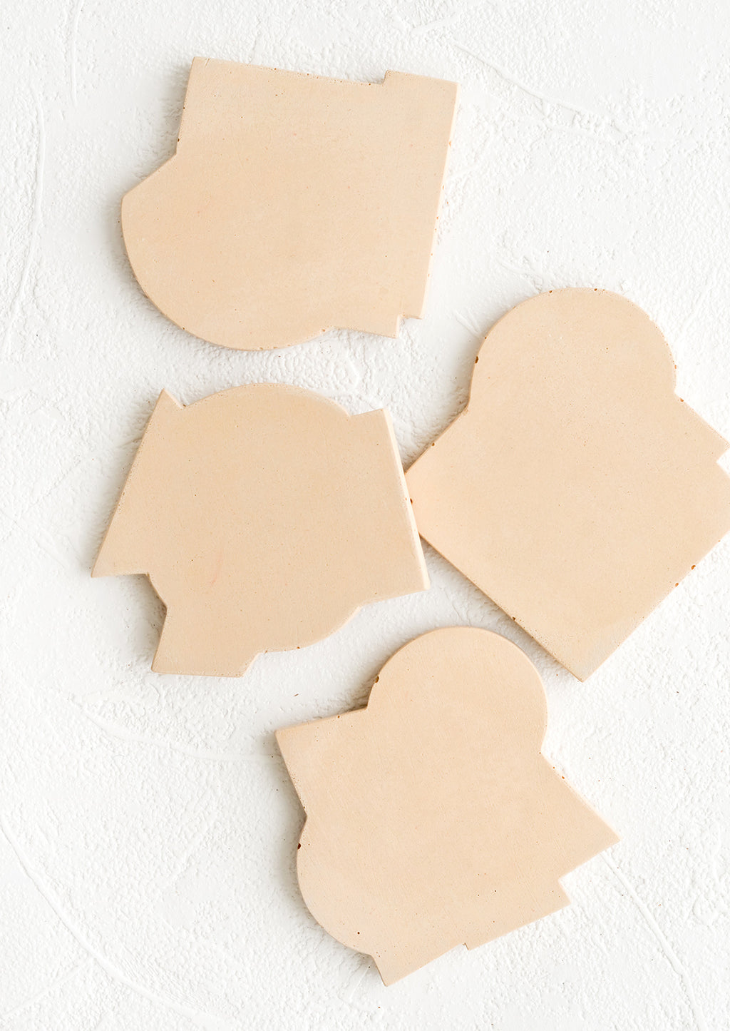 Straw: Four concrete coasters in nude color with unique abstract shapes.