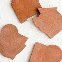 Ore: Four concrete coasters in rust color with unique abstract shapes.