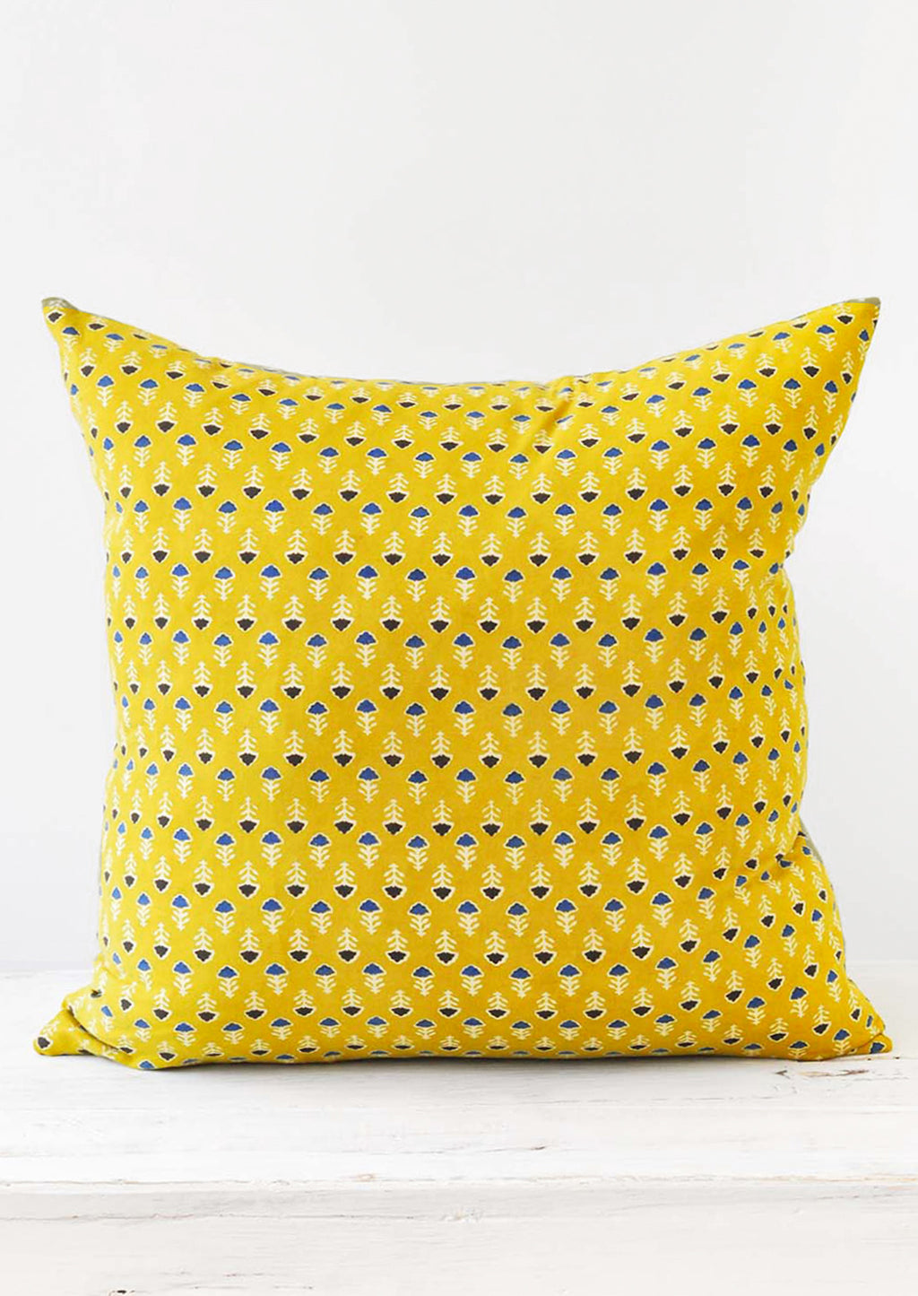 1: A block printed pillow with a yellow, blue, and white floral design.
