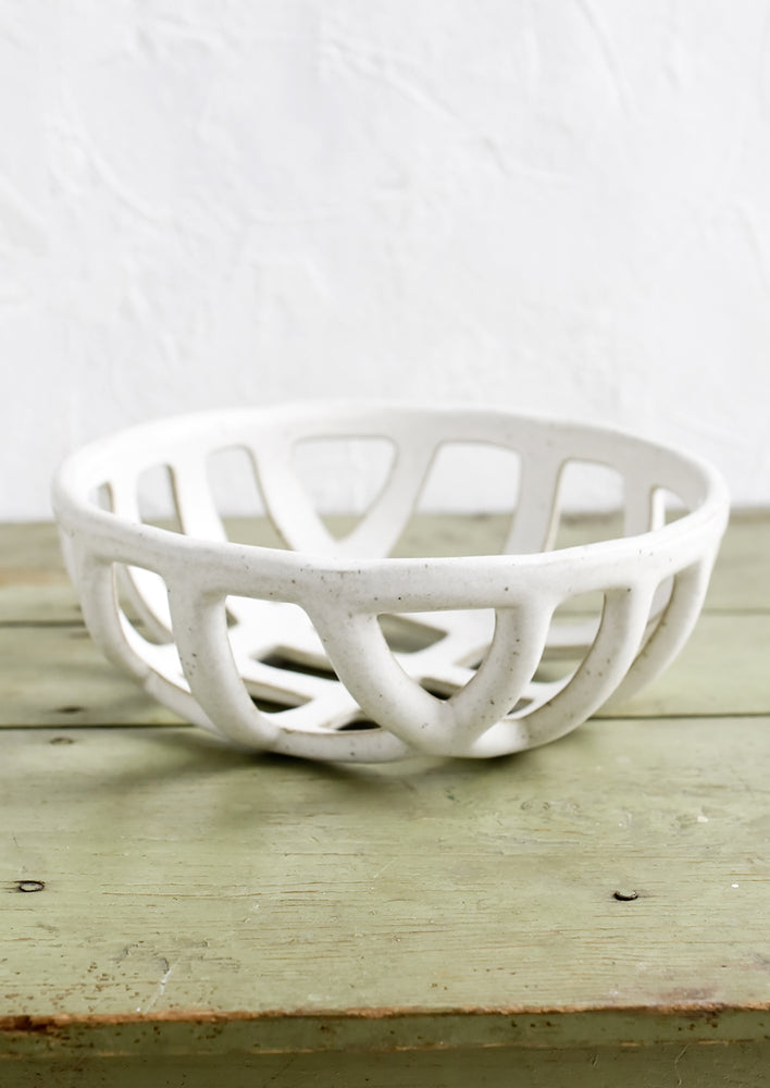 A white ceramic fruit bowl with open weave design.