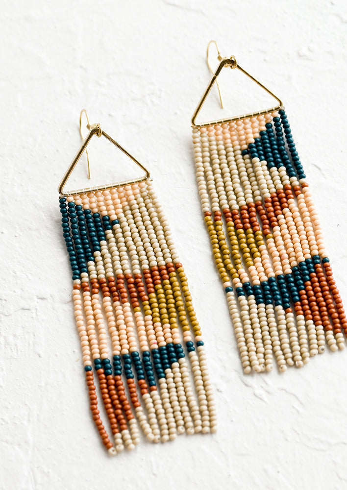 A pair of beaded strand earrings hanging from triangle metal frame.