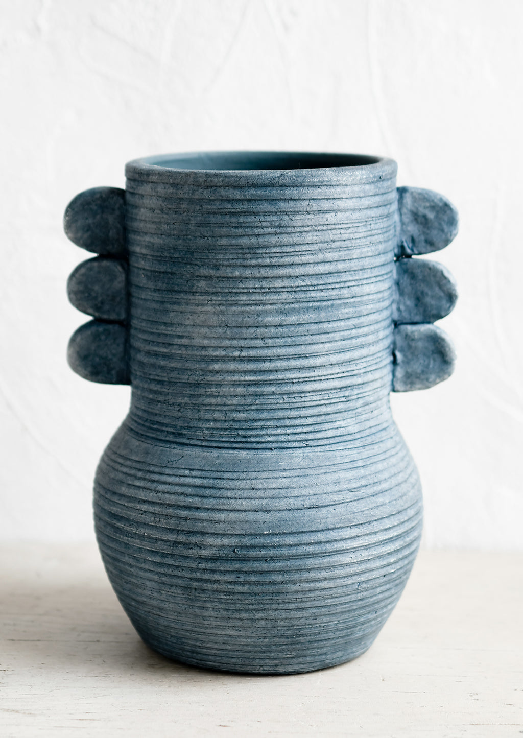 1: An ocean blue ceramic vase with etched ribbing and side tabs.