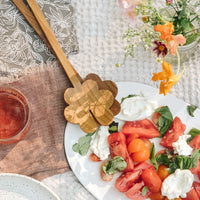 2: A picnic scene with tomato salad and wooden serving set.