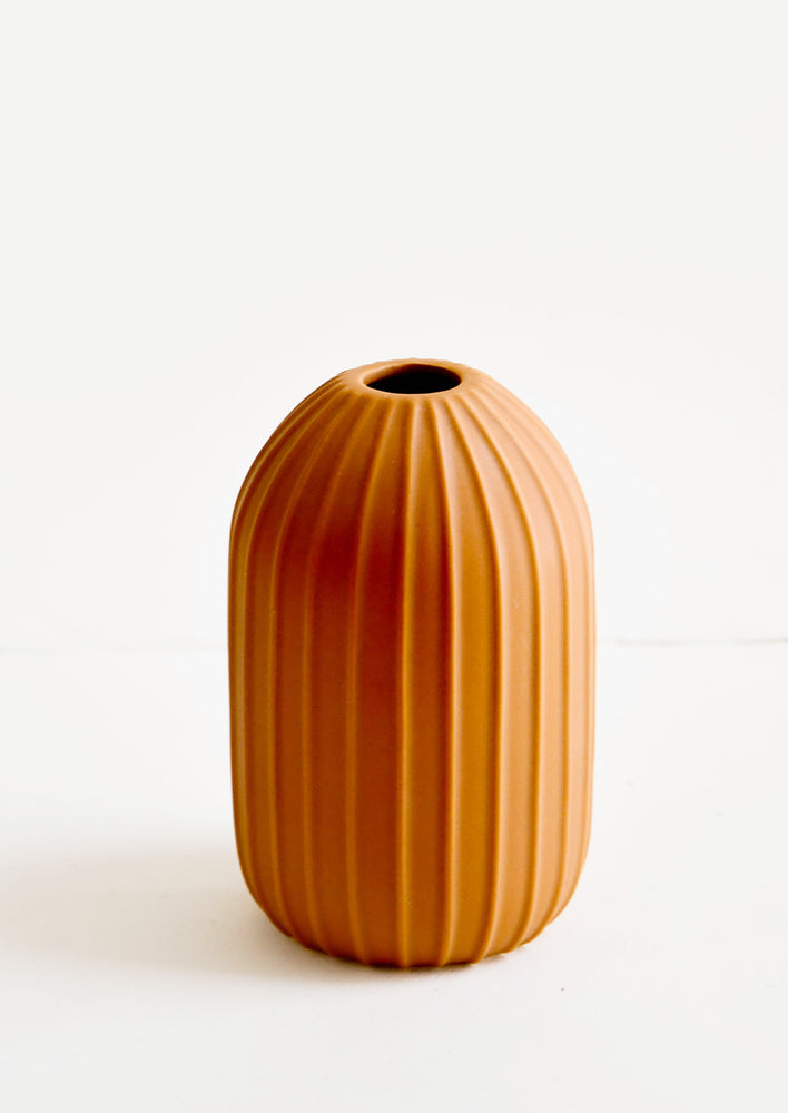 Terracotta colored ceramic vase with vertical ribbed texture and narrow opening
