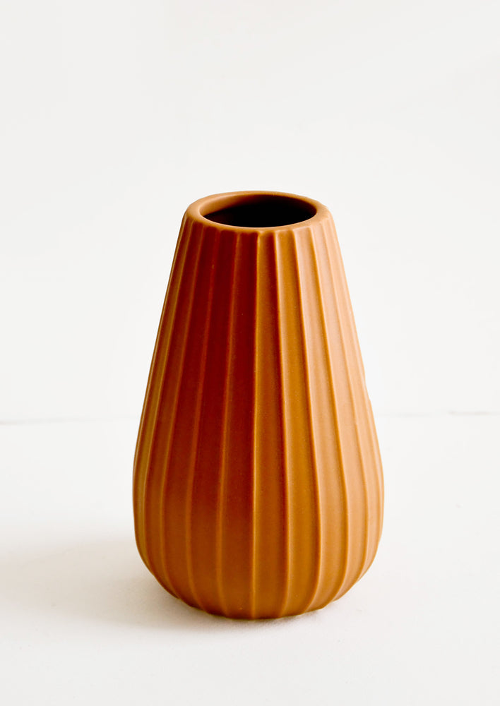 Terracotta colored ceramic vase with vertical ribbed texture and wide mouth opening