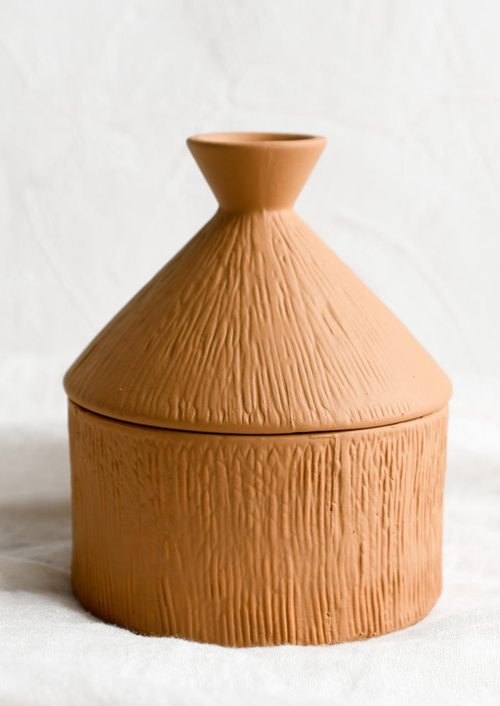 A tagine-shaped terracotta lidded storage jar.