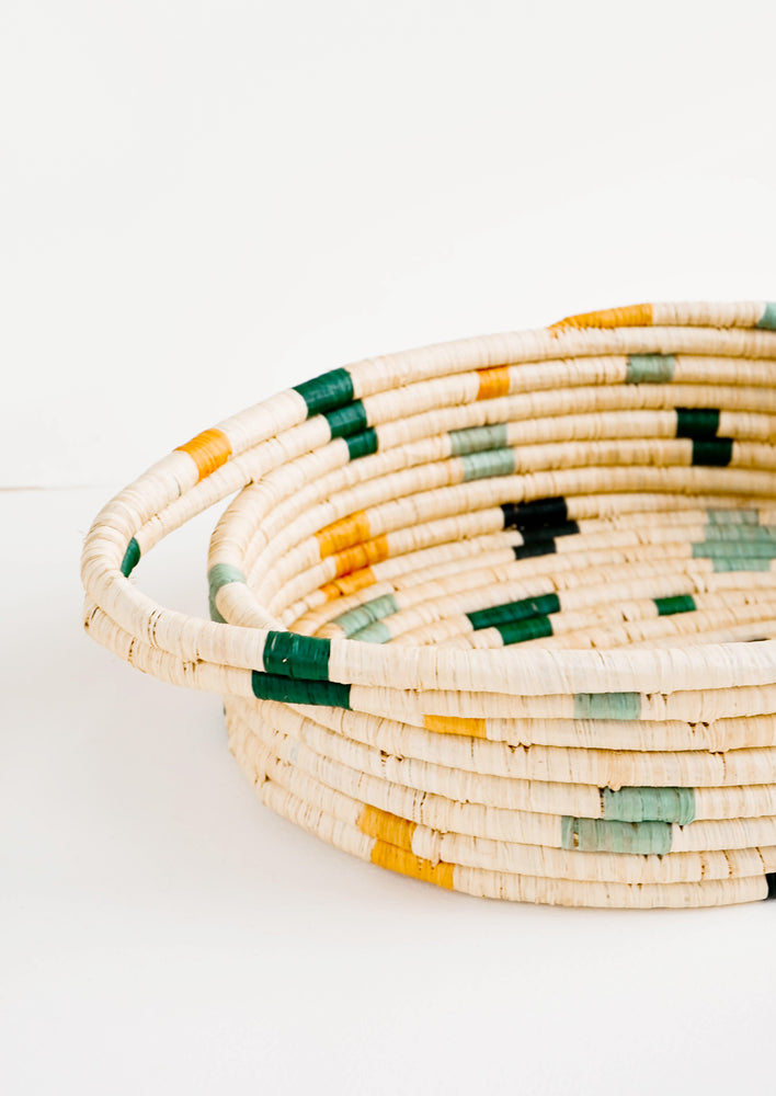 Woven raffia basket with handles at sides and colorful spots