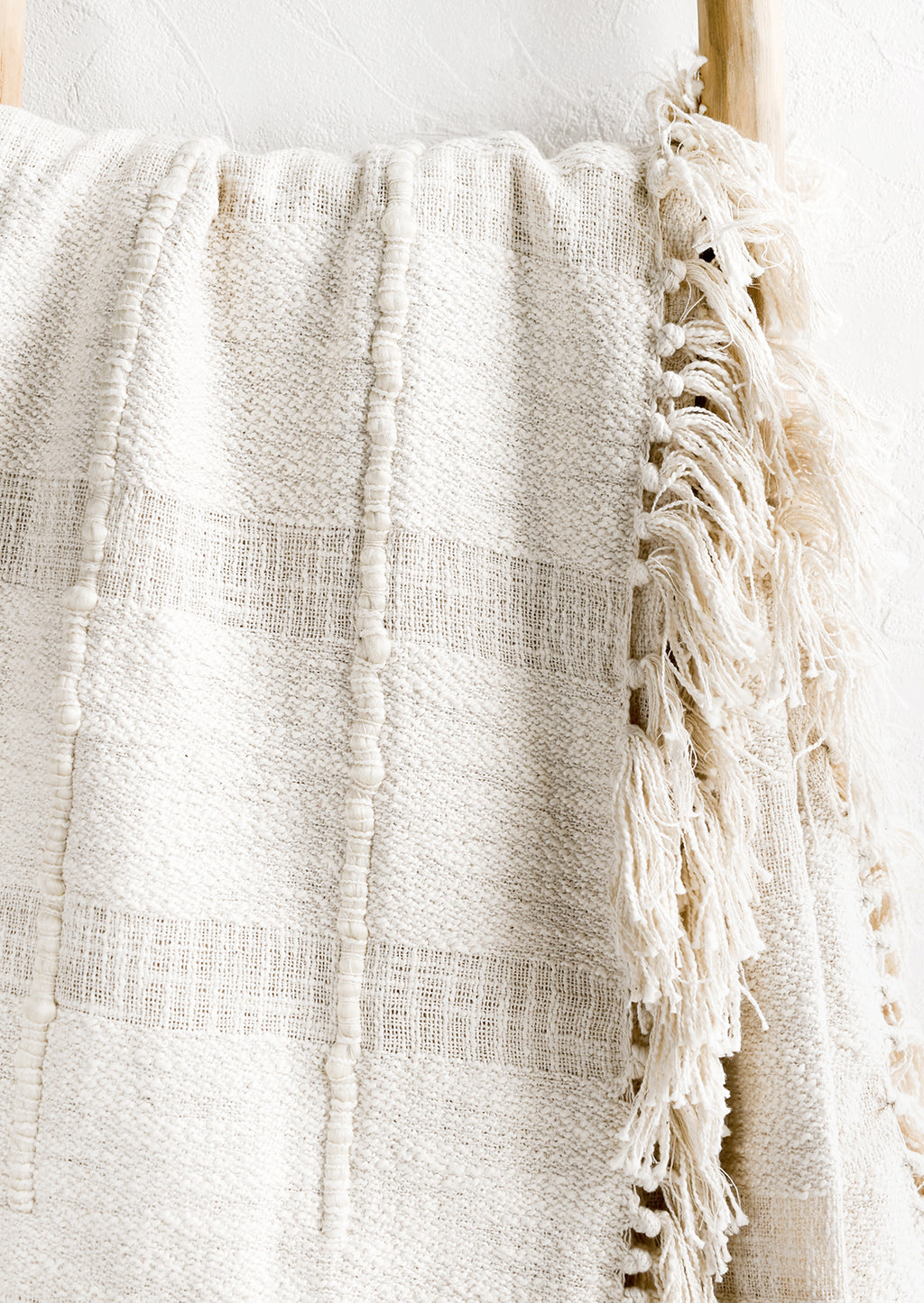 3: A natural cotton throw with paneling detailing and fringed trim.