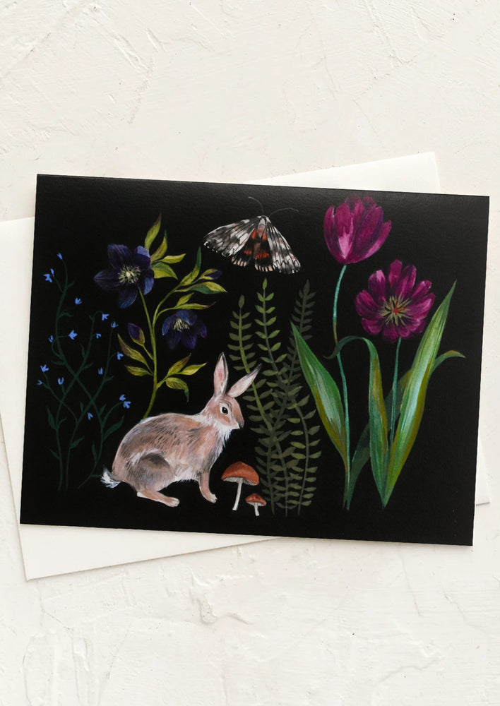 An illustrated greeting card with flora and fauna on black background.