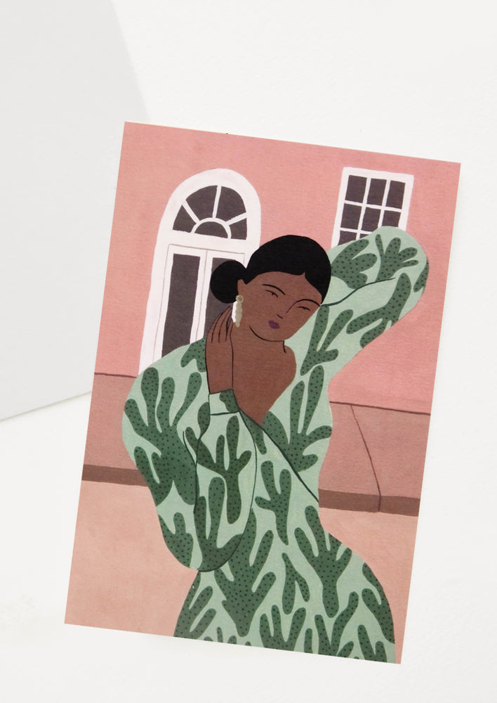 Oversized greeting card with woman in leaf print dress posing in front of a building